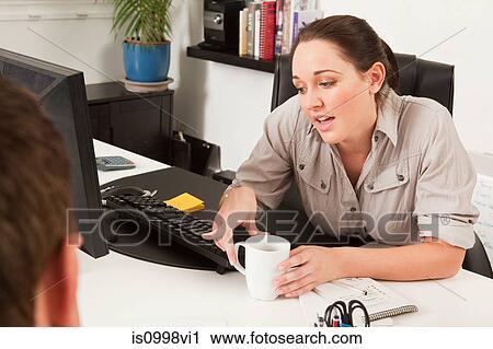 Stock Image - Female worker discussing work with a colleague. Fotosearch