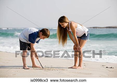 Girl and boy drawing pictures in the sand View Large Photo Image Stock Image - Girl and boy drawing pictures in the sand. Fotosearch