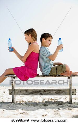 Girl and boy holding bottles of water on a beach View Large Photo Image Stock Photo - Girl and boy holding bottles of water on a beach. Fotosearch