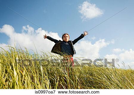 Stock Photo - Girl holding arms out in long grass. Fotosearch