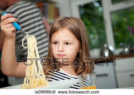 Girl holding up spaghetti at table View Large Photo Image Stock Photo - Girl holding up spaghetti at table. Fotosearch