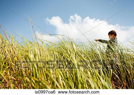 Stock Photograph - Girl pointing in long grass. Fotosearch