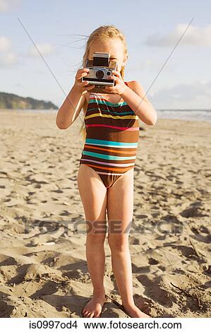 Picture - Girl using instant camera on beach. Fotosearch