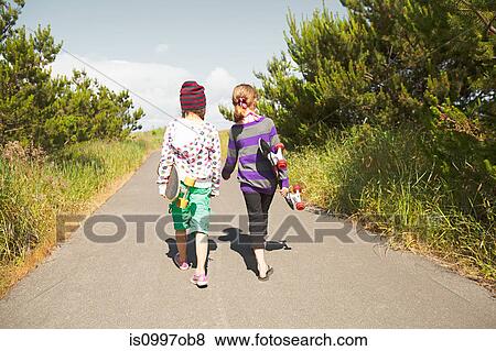 Girls carrying skateboards along rural road View Large Photo Image Stock Photo - Girls carrying skateboards along rural road. Fotosearch