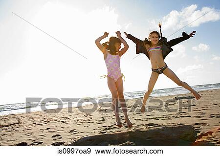 Girls jumping on sand at beach View Large Photo Image Stock Photo - Girls jumping on sand at beach. Fotosearch