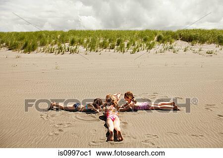 Girls lying on sand at beach View Large Photo Image Stock Image - Girls lying on sand at beach. Fotosearch