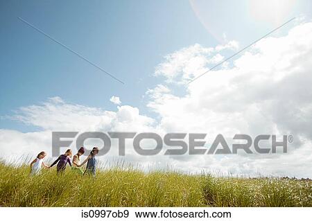 Girls walking through long grass View Large Photo Image Stock Photo - Girls walking through long grass. Fotosearch