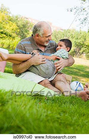Stock Image - Grandfather playing with grandson in park. Fotosearch