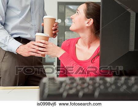 Stock Photograph - Male colleague bringing female colleague coffee. Fotosearch