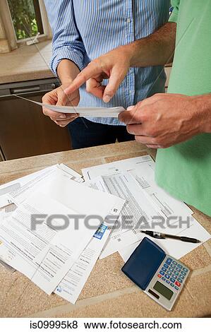 Mature couple looking at household bills, close up View Large Photo Image Stock Photo - Mature couple looking at household bills, close up. Fotosearch