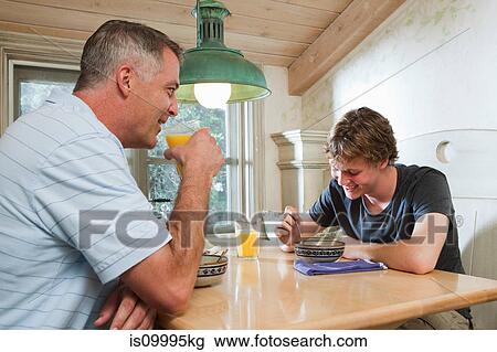 Stock Image - Mature man and son sitting together over breakfast. Fotosearch