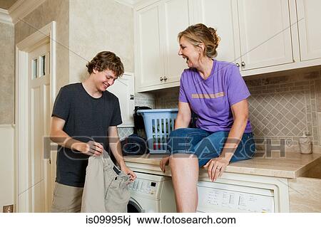 Mature woman and son in laundry room View Large Photo Image Stock Image - Mature woman and son in laundry room. Fotosearch