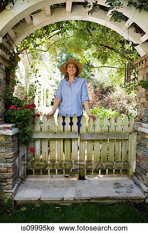 Mature woman standing under garden arch, portrait View Large Photo Image Stock Image - Mature woman standing under garden arch, portrait. Fotosearch