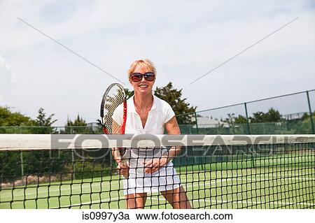 Mature woman waiting for ball at net during game of tennis View Large Photo Image Stock Image - Mature woman waiting for ball at net during game of tennis. Fotosearch