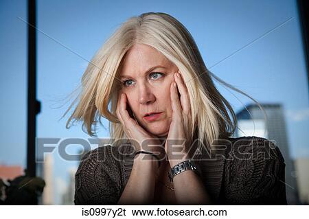 Mature woman with head in hands looking concerned View Large Photo Image Stock Photograph - Mature woman with head in hands looking concerned. Fotosearch
