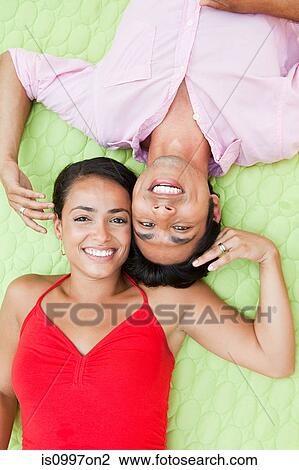 Stock Image - Mid adult couple lying on blanket outdoors, portrait. Fotosearch