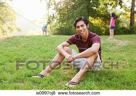 Mid adult man sitting in park, portrait View Large Photo Image Stock Photo - Mid adult man sitting in park, portrait. Fotosearch