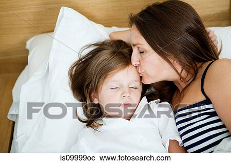 Mid adult woman kissing sleeping daughter View Large Photo Image Stock Image - Mid adult woman kissing sleeping daughter. Fotosearch