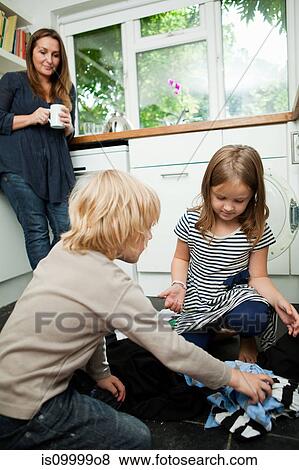 Mid adult woman watching children sort laundry View Large Photo Image Stock Photo - Mid adult woman watching children sort laundry. Fotosearch