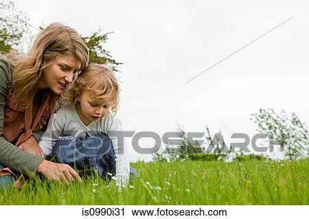 Stock Image - Mother and daughter picking daisies. Fotosearch
