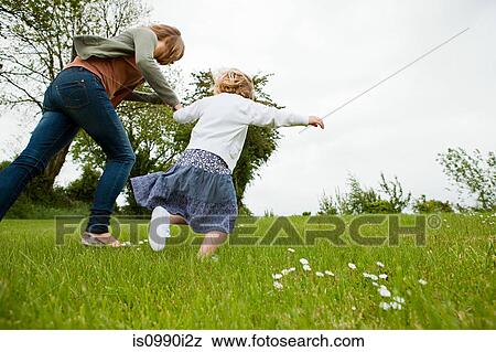 Stock Photo - Mother and daughter running in field. Fotosearch