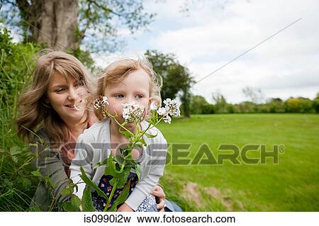Mother and daughter sitting in field with wildflowers View Large Photo Image Stock Photo - Mother and daughter sitting in field with wildflowers. Fotosearch