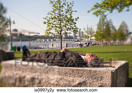 Senior man lying on a stone block in park View Large Photo Image Stock Photo - Senior man lying on a stone block in park. Fotosearch