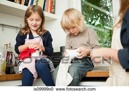 Siblings drying cups on kitchen counter View Large Photo Image Stock Image - Siblings drying cups on kitchen counter. Fotosearch