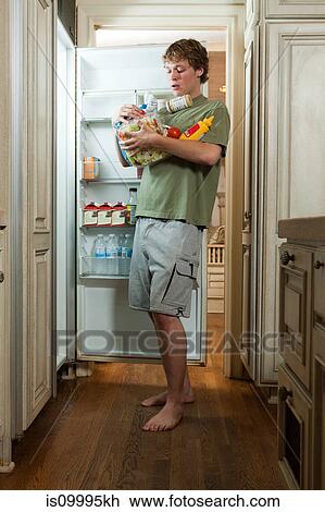 Teenage boy taking food from fridge View Large Photo Image Stock Image - Teenage boy taking food from fridge. Fotosearch