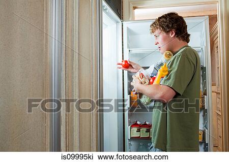 Teenage boy taking food from fridge View Large Photo Image Stock Image - Teenage boy taking food from fridge. Fotosearch