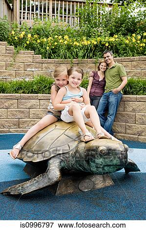 Two girls sitting on top of tortoise statue at the zoo View Large Photo Image Stock Photo - Two girls sitting on top of tortoise statue at the zoo. Fotosearch