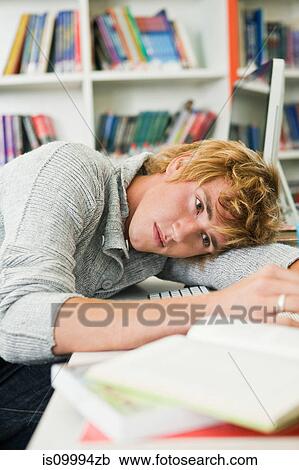 Stock Image - University student daydreaming at desk. Fotosearch