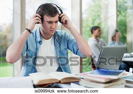 Stock Image - University student putting on headphones. Fotosearch