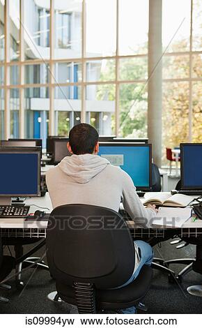 Stock Photo - University student working at computer desk, rear view. Fotosearch