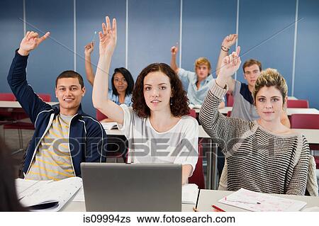 Stock Photograph - University students holding up hands in class. Fotosearch