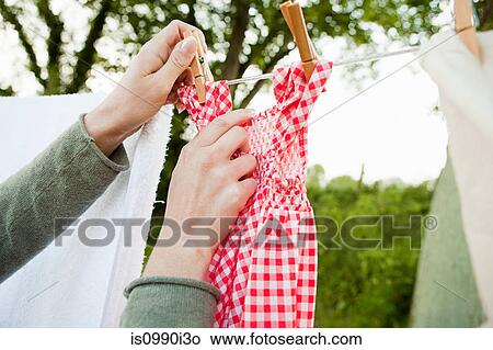 Picture - Woman hanging laundry on clothesline. Fotosearch