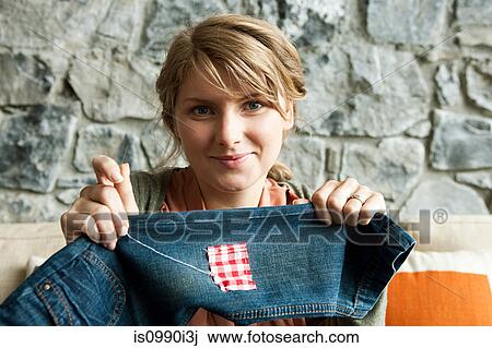 Stock Image - Woman repairing jeans. Fotosearch