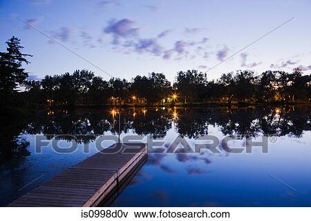 Wooden dock and view of illuminated Ile des Moulins on the Mille-Iles river at dawn, Old Terrebonne, Lanaudiere, Quebec, Canada View Large Photo Image Stock Photo - Wooden dock and view of illuminated Ile des Moulins on the Mille-Iles river at dawn, Old Terrebonne, Lanaudiere, Quebec, Canada. Fotosearch