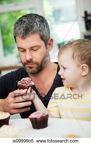 Young boy passing cupcake to his father View Large Photo Image Stock Photography - Young boy passing cupcake to his father. Fotosearch