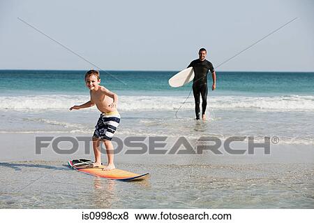 Stock Photo - Young boy surfing in shallow water. Fotosearch
