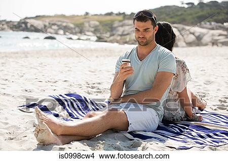 Young couple relaxing back to back on a beach View Large Photo Image Picture - Young couple relaxing back to back on a beach. Fotosearch