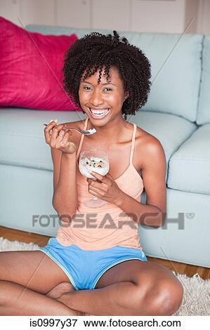 Stock Photo - Young woman eating desert while relaxing at home. Fotosearch