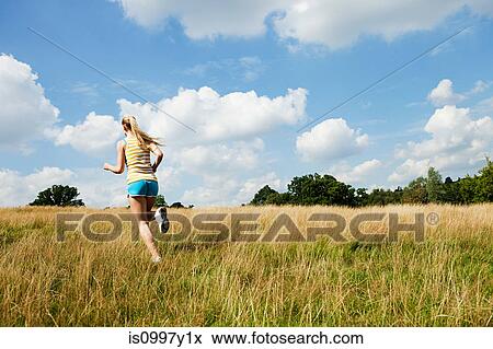 Young woman jogging through a field on a sunny day View Large Photo Image Stock Photo - Young woman jogging through a field on a sunny day. Fotosearch