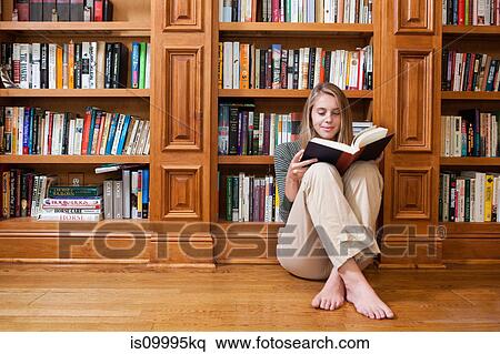 Young woman reading on floor by bookshelves View Large Photo Image Stock Photography - Young woman reading on floor by bookshelves. Fotosearch