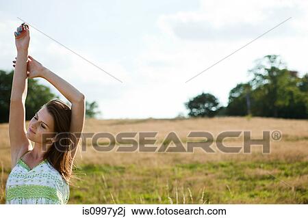 Young woman stretching in a field View Large Photo Image Stock Image - Young woman stretching in a field. Fotosearch