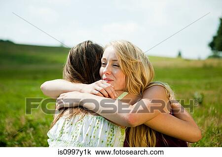 Young women embracing in a field View Large Photo Image Stock Image - Young women embracing in a field. Fotosearch