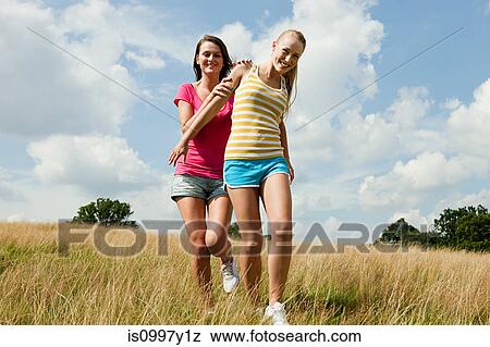 Young women running through a field together View Large Photo Image Stock Photo - Young women running through a field together. Fotosearch