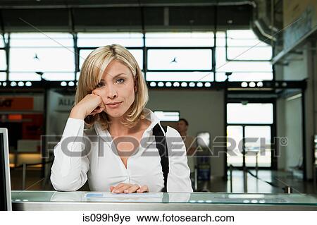 Stock Image - Bored woman at check in desk of airport. Fotosearch
