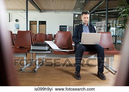 Businessman using laptop in departure lounge of airport View Large Photo Image Stock Image - Businessman using laptop in departure lounge of airport. Fotosearch