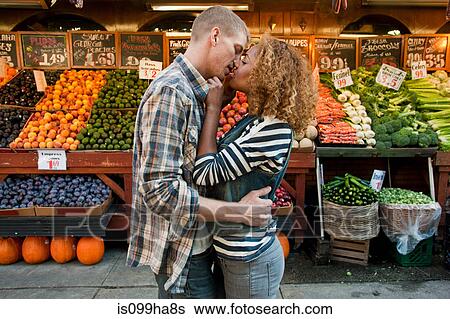 Stock Photograph - Couple kissing by market stall. Fotosearch